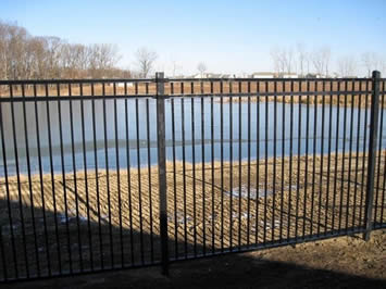 Black basic steel fencing are installed around a small pond to minimize water hazards.