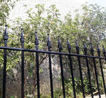 Black rod top fence panels with finials are used to protect backyards.