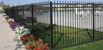 A series of black rod top steel fence panels are erected to safeguard a playground